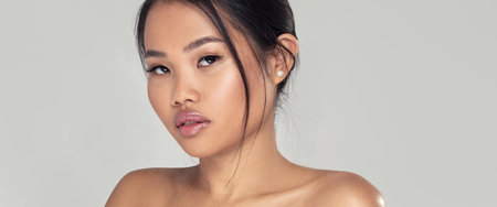 Beauty closeup portrait of elegant, natural asian woman with glamour delicate makeup posing on studio background. Girl looking at the camera.の写真素材