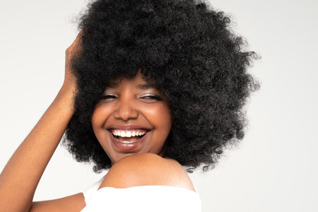 Closeup beauty portrait of natural, beautiful, young girl with afro hairstyle and big toothy smile. Real people emotions.の写真素材