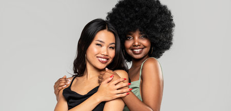 Beauty asian woman posing with her friend with afro hairstyle. Cheerful, elegant girls standing together, looking at the camera and smiling happily. Copy space. Real people.の写真素材