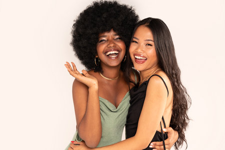 Beauty asian woman posing with her friend with afro hairstyle. Cheerful, elegant girls standing together, looking at the camera and smiling happily. Copy space. Real people.の写真素材