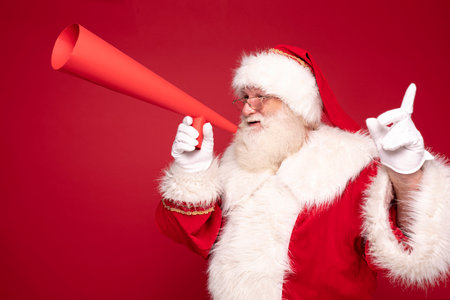 Christmas are coming! Real Santa Claus with red megaphone in studio.の写真素材