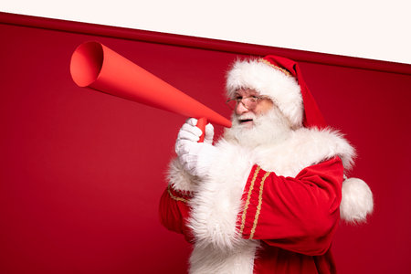 Christmas are coming! Real Santa Claus with red megaphone in studio.の写真素材