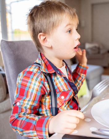 Hungry little kid waiting for the dinner at home, holding fork in hand.の写真素材