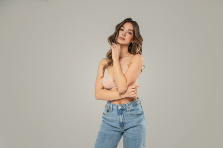 Fashionable beautiful young woman posing on studio background in jeans, looking at the camera. A lot of copy space.の写真素材