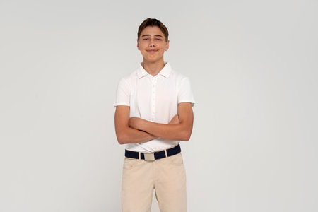 Teenage boy dressed in white shirt, trendy elegant clothes, posing at studio. Portrait of handsome teen boy over white background smiling and looking at the camera.の写真素材