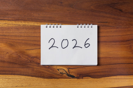 New Year written on white notepad on wooden table background.