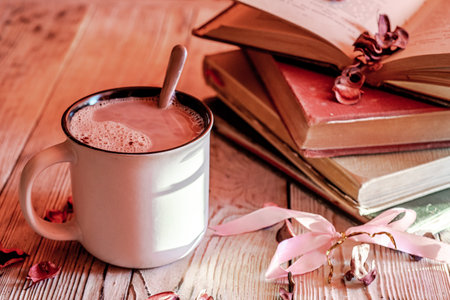 Mug of hot chocolate near a stack of vintage old books on wooden rustic table.の写真素材