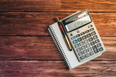 Top view of a calculator with a pen and notebook on a rustic wood table. Concept of business, finance, educationの写真素材