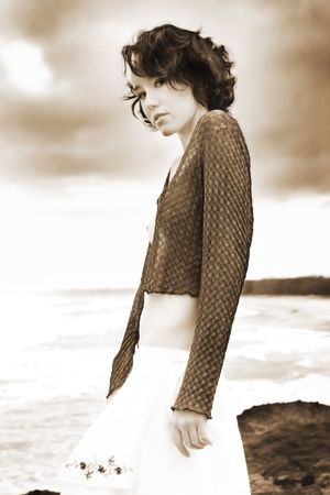 A beautiful girl stands on a headland overlooking the oceanの写真素材