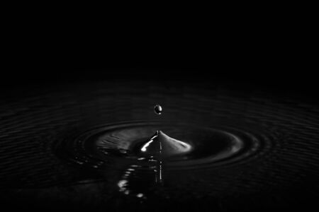 Water drop highlit in dark surroundingsの写真素材