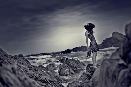 A woman is stranded on the rocks of a beach