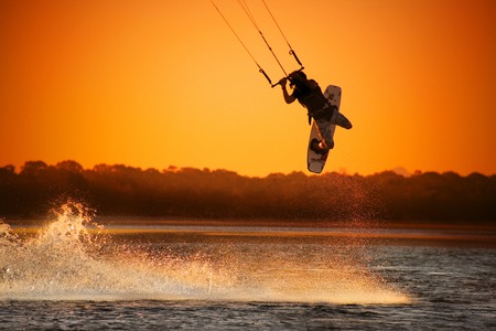 Kite boarder performing a jump at sunset