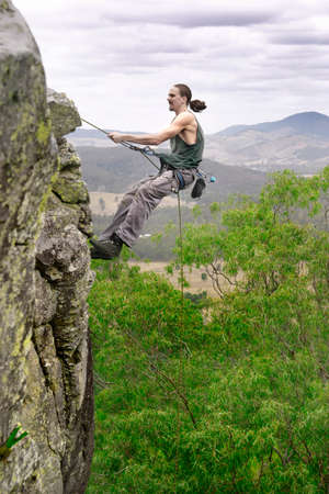 Man abseils down cliff with nice view behind