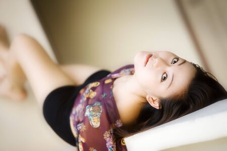 Beautiful Asian woman lays on her back looking at cameraの写真素材
