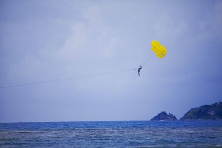 person parasailing with yellow parasail on clear blue dayの写真素材