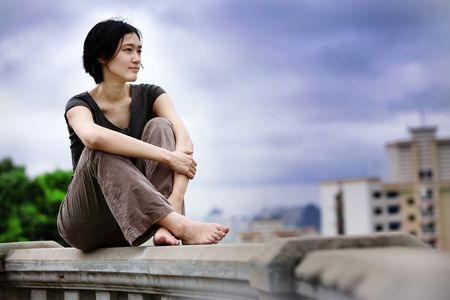 Asian girls sits at lookout overlooking cityの写真素材