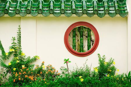 Round Chinese window in wall in gardenの写真素材
