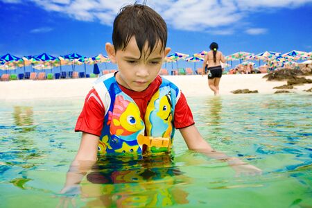 Boy plays in tropical waters of Thailand beachの写真素材
