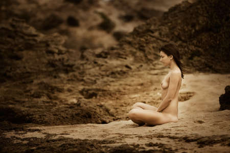 Naked woman meditates on a beachの写真素材