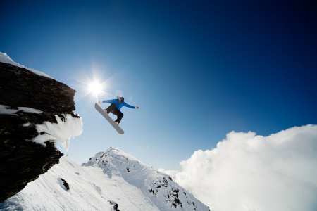Snowboarder jumping through air after rock drop