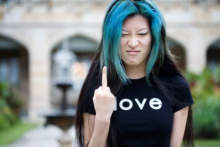 Upset girl making rude gesture with love printed on shirtの写真素材