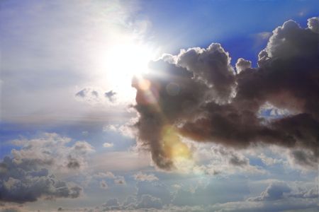 Sun bursting through clouds with beams and flareの写真素材