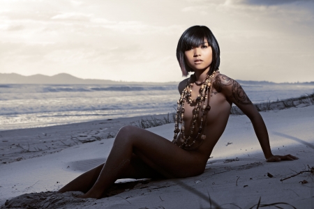 Beautiful Asian girl naked on beach wearing lots of beadsの写真素材
