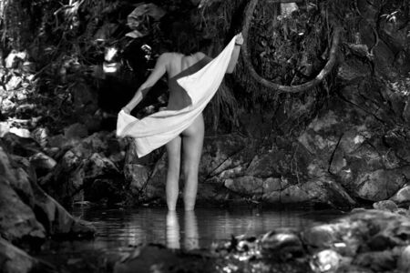 Naked woman towling off after swim in waterholeの写真素材