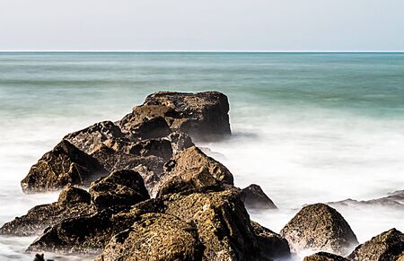 A tongue of rocks entering the sea from the beach