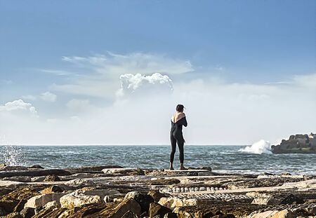 A surfer without a plate taking pictures with his cell phone on the pier