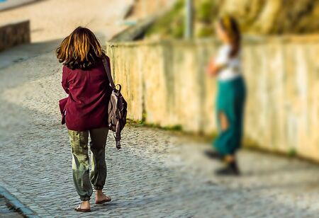 Woman with bordeaux jacket walking at the entrance of the beach