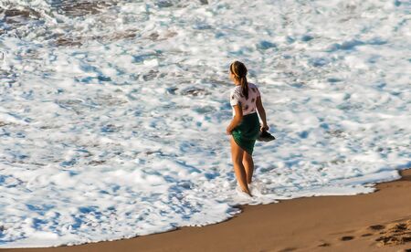 Woman with green skirt cooling her feet in the oceanの写真素材
