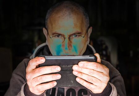 Man with glasses in the light of a tablet