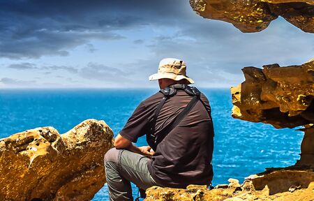 Man sitting on a rock looking out to sea