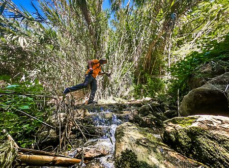 Man with hat jumping over a streamの写真素材