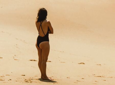 A woman in a black swimsuit alone on the beachの写真素材