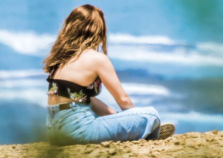 A young girl caught on the beach posing in front of her friendの写真素材