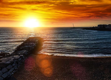 Seascape at sunset close to the blue hour with the sun emanating rays and the golden skyの写真素材