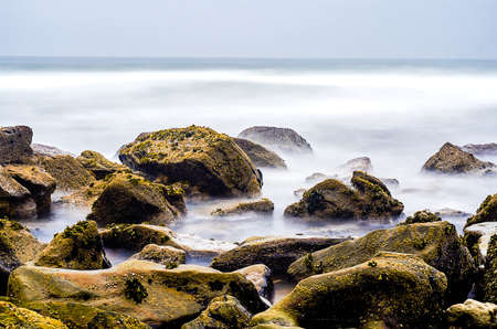Ocean landscape with a rocky beach with neutral density filter with wide exposureの写真素材