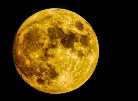 Full moon in the foreground with a zoom of 2000 in golden hue on a clear nightの写真素材