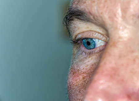 Profile portrait of a blue-eyed man with half a face in sightの写真素材