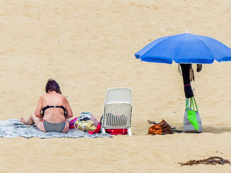 Moment on a beach with an umbrella in cloudy weather without sunの写真素材