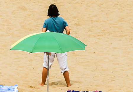 Moment on a beach with an umbrella in cloudy weather without sunの写真素材