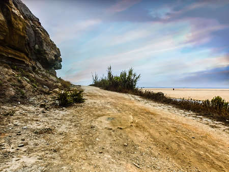 Image from a country road leading to the sea with a cloudy skyの写真素材
