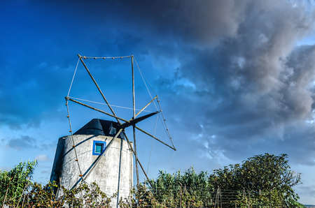 Landscape with an old windmill near sunset on a background of blue sky with a few cloudsの写真素材