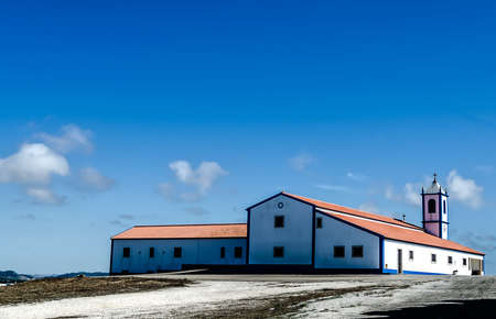 A chapel on top of a hill with an intense blue sky with a few cloudsの写真素材