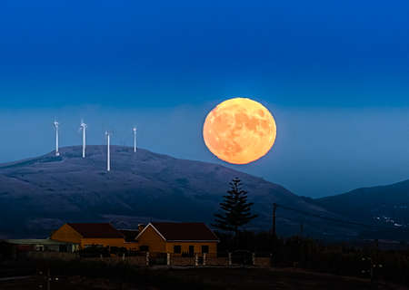 Landscape with moonrise behind the hills at sunset between day and night