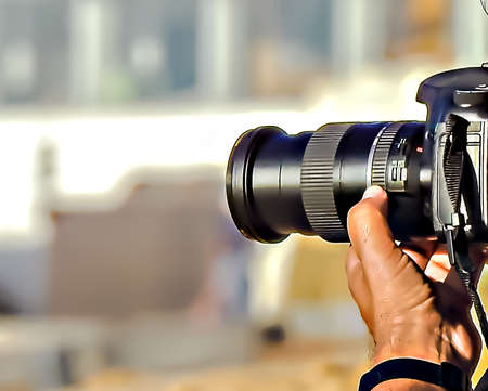 The hand of a photographer setting up the camera at the beach on a blurred backgroundの写真素材