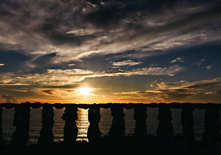 Sunset seen from behind a stone railing on the Portuguese coast of the Atlantic Oceanの写真素材