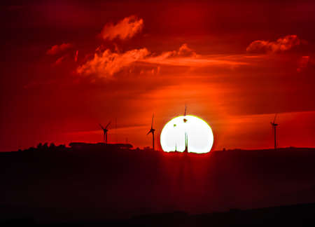 The sun rose over the hills with windmills in bright orange colorsの写真素材